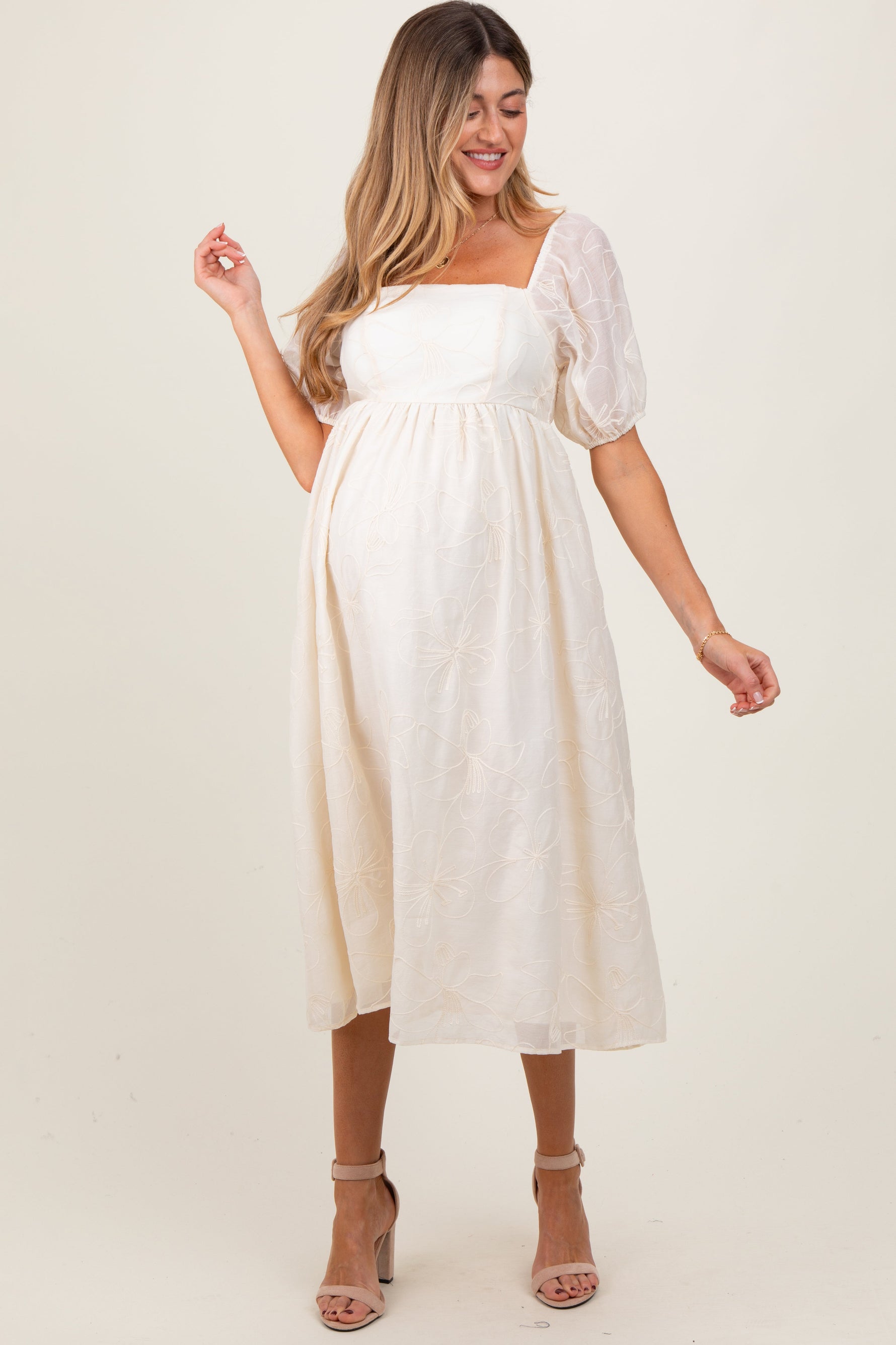 Cream maternity midi dress with delicate floral embroidery, puff sleeves, and a comfortable fit.