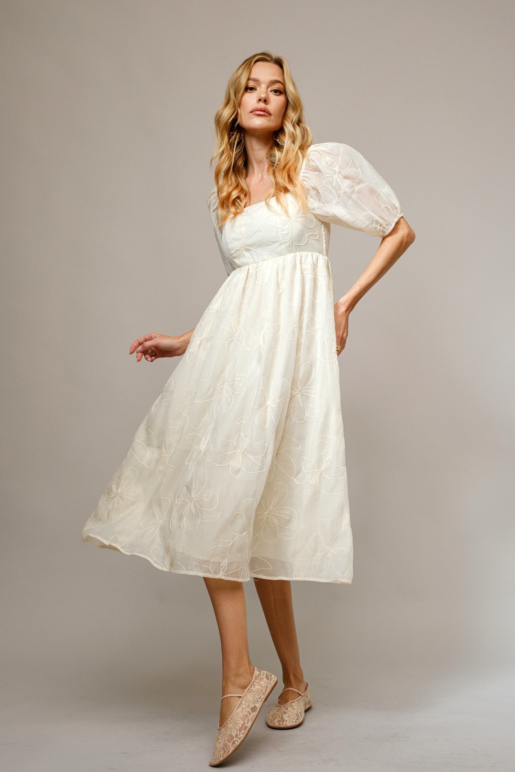 Cream maternity midi dress with delicate floral embroidery, puff sleeves, and a comfortable fit.