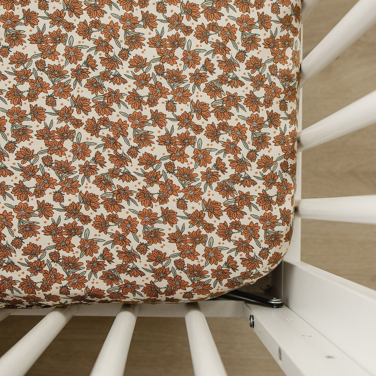 Cream magnolia bamboo stretch crib sheet fitted on a standard crib mattress in a nursery.