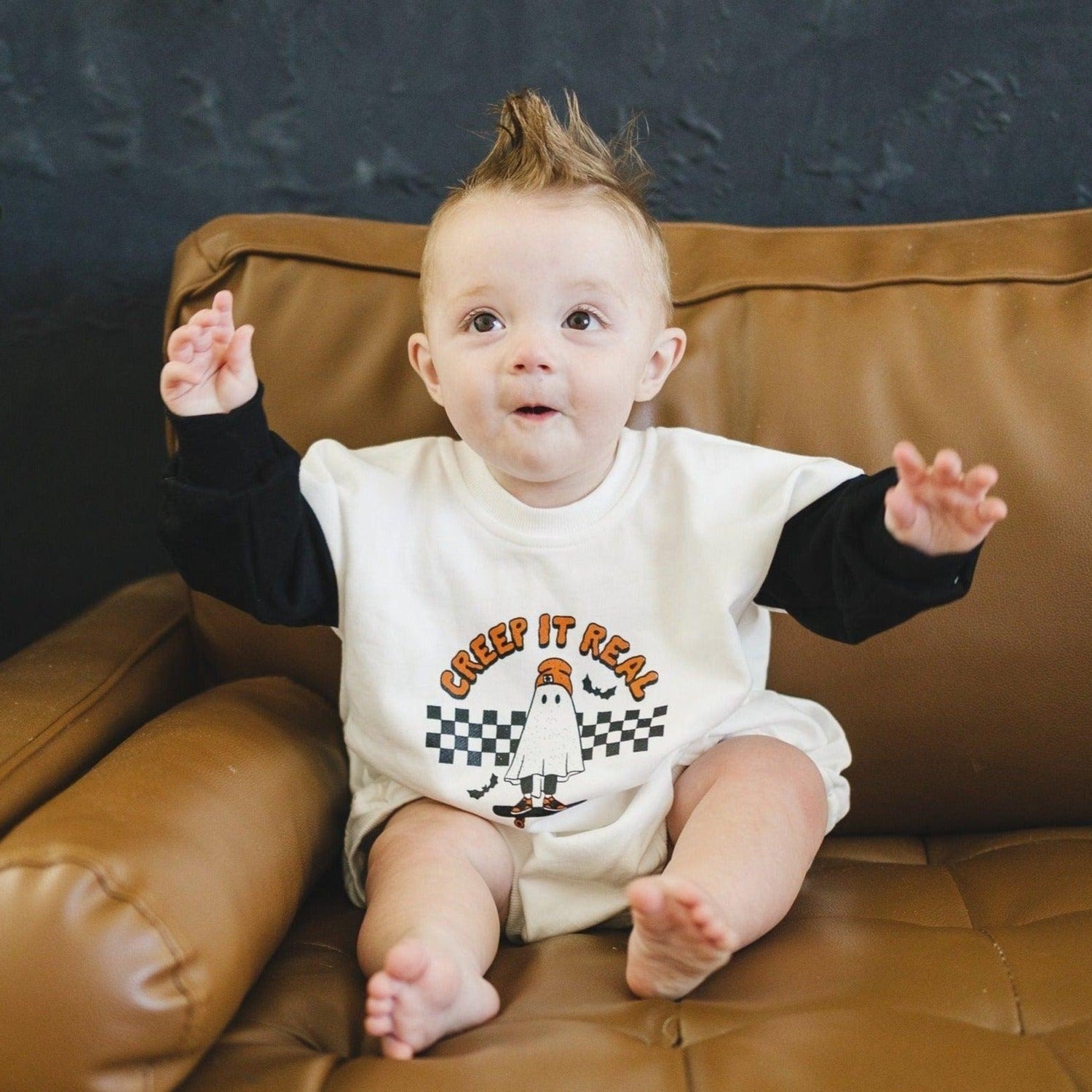 Halloween sweatshirt romper with white body, black sleeves, and screenprinted "Creep It Real" graphic.