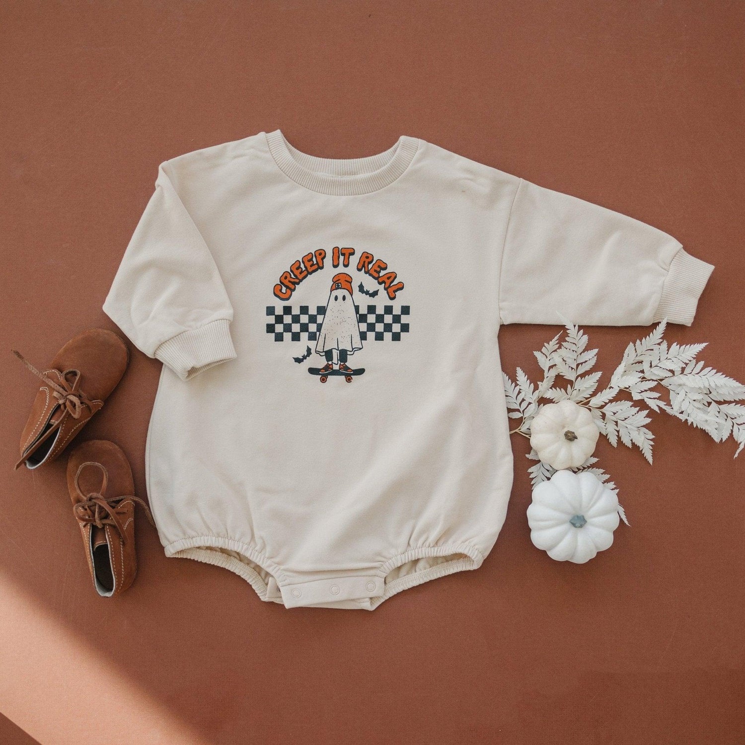 Long-sleeve sweatshirt romper with "Creep It Real" Halloween graphic and snaps at the crotch.