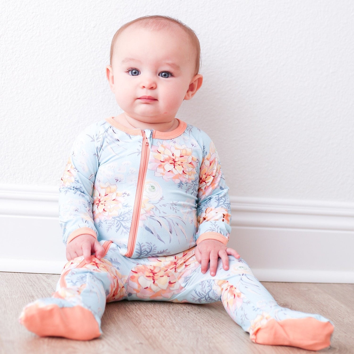 Baby footie pajama in a dahlia floral print with covered feet and a full-length front zipper.