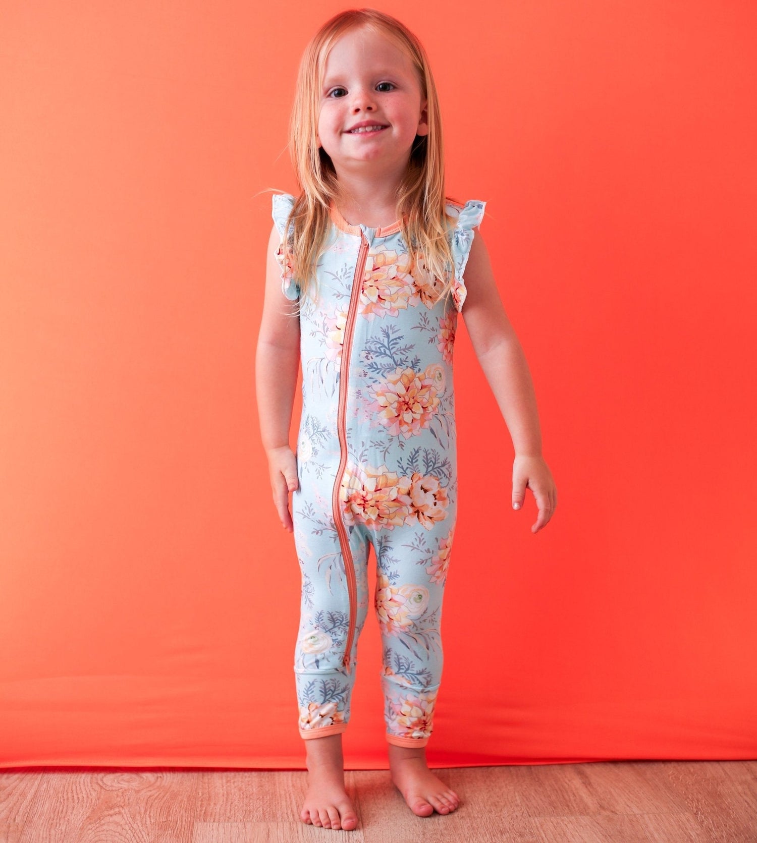 Sleeveless flutter-sleeve baby romper in a dahlia floral pattern with a front zipper.