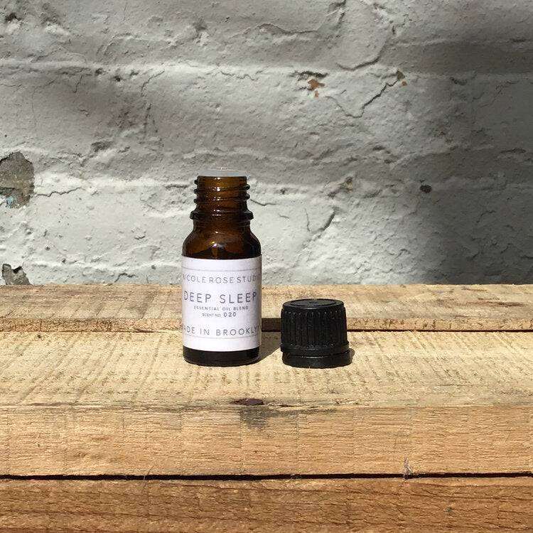 Deep Sleep Essential Oil Blend bottle on wooden surface, offering lavender aroma for sleep aid and relaxation.