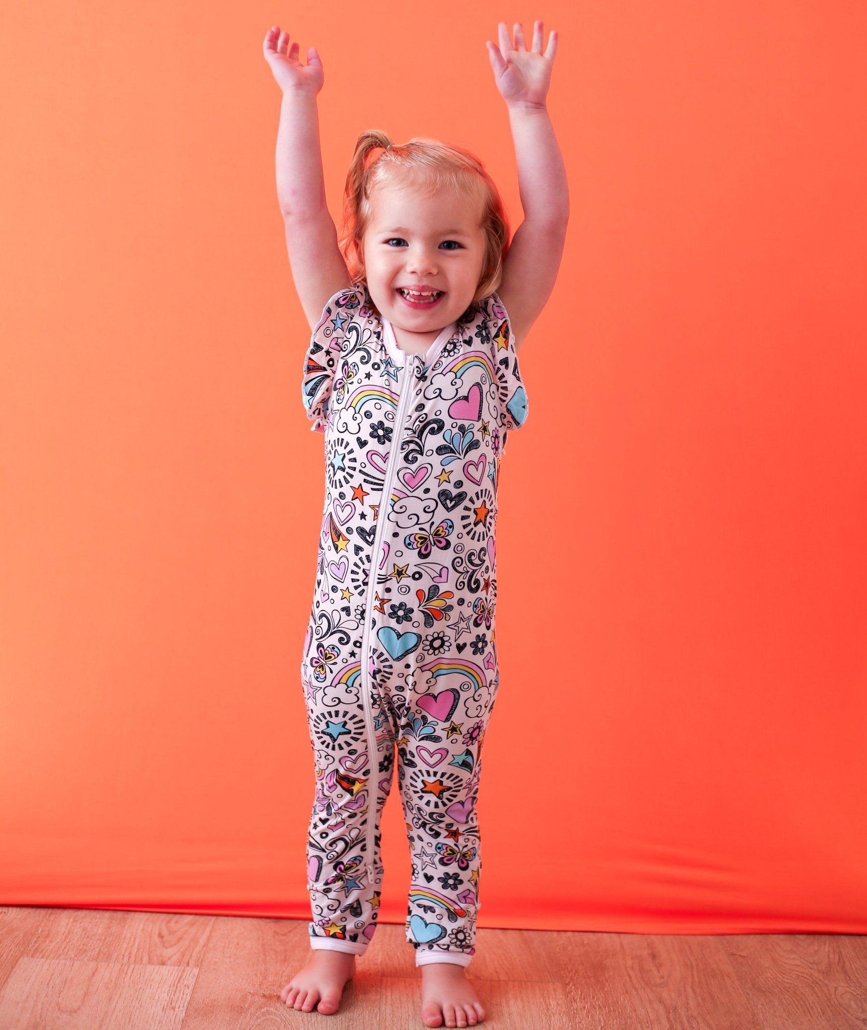 Flutter sleeve baby romper in a playful doodle print with dual front zippers.