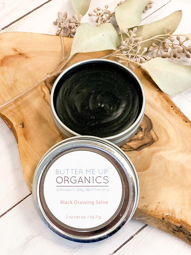 Organic black drawing salve in a tin container for bee stings and skin rashes.