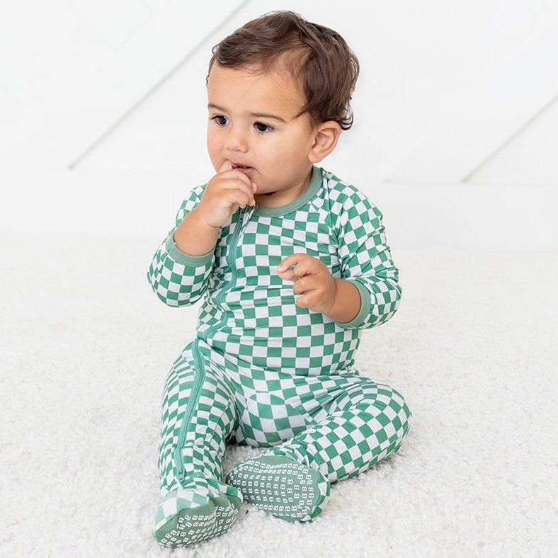 Baby footie pajamas in a green and white checkered pattern with a full-length front zipper and footed legs.
