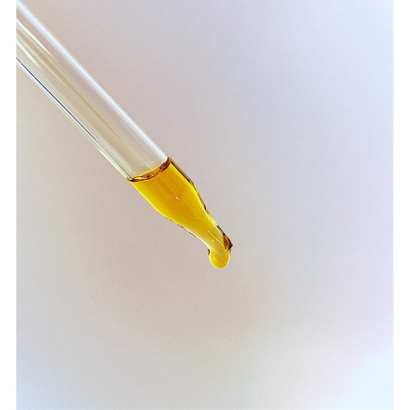 Organic Face & Eye Serum dropper with golden oil against white background.