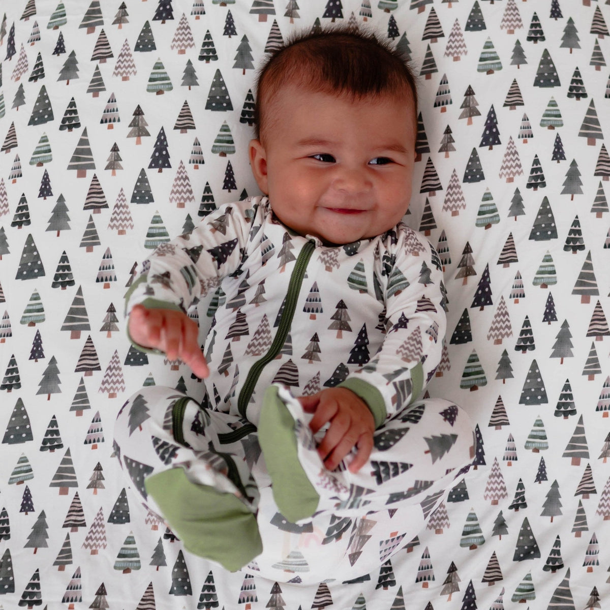 Baby footie pajamas with an all-over evergreen fir tree print and a full-length front zipper