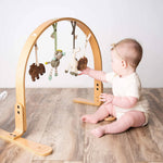 Modern Nursery natural wooden baby play gym with organic hanging toys.