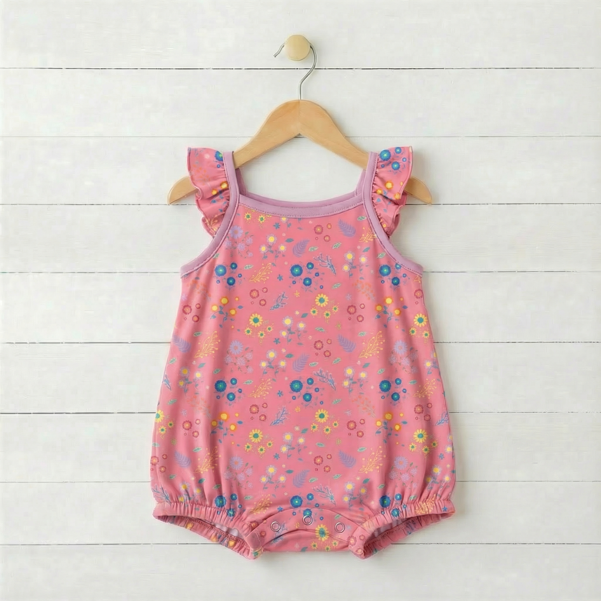 Baby bubble romper with flower confetti print, flutter sleeves and snap closures along the legs