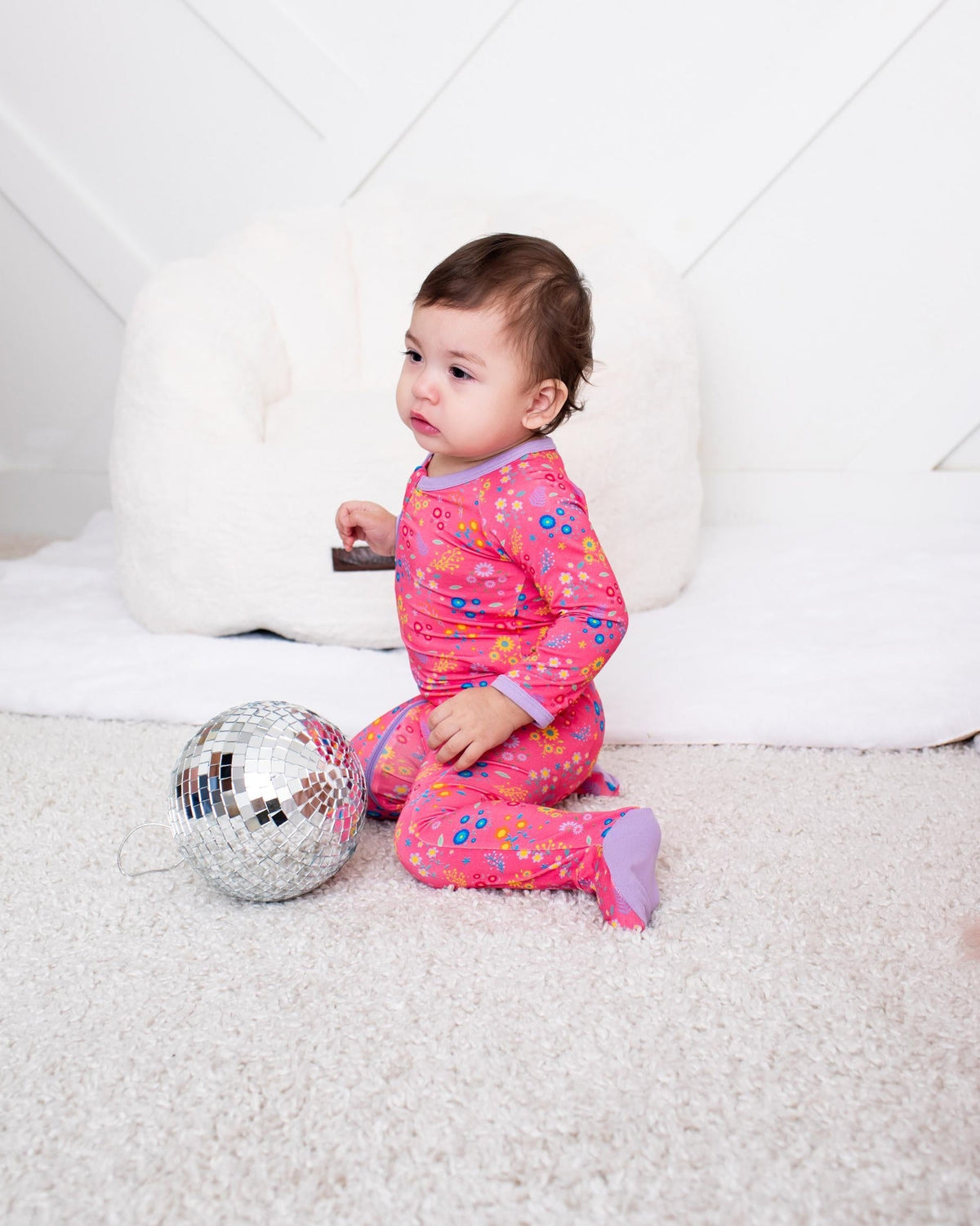 Baby footie pajamas in white with a scattered multicolor flower confetti print and front two-way zipper
