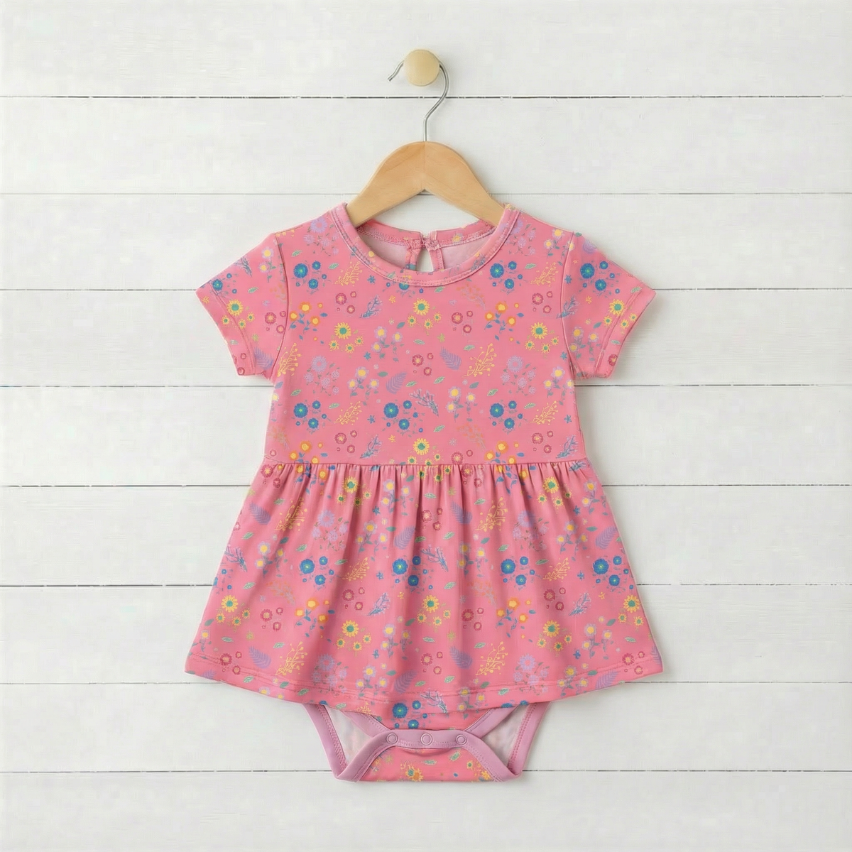 Short sleeve baby bodysuit dress in a flower confetti print with a full skirt and snaps at the bottom