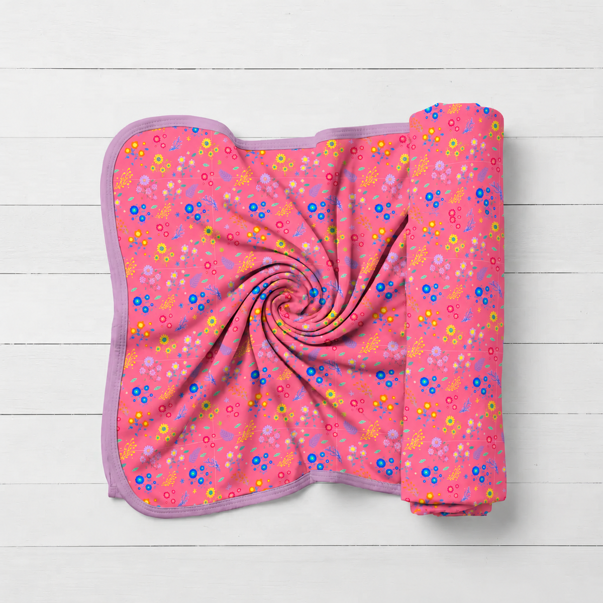 Swaddle blanket with scattered flower confetti print on a light background