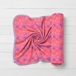 Swaddle blanket with scattered flower confetti print on a light background