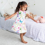 Pink short-sleeve toddler dress on a smiling child holding a teddy bear