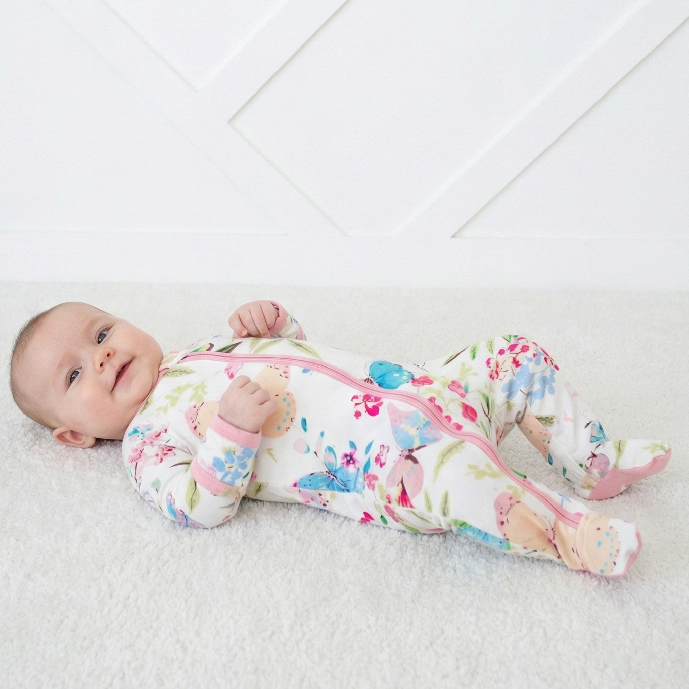 Footie pajamas in a pink floral and butterfly print with a full-length front zipper and covered feet.