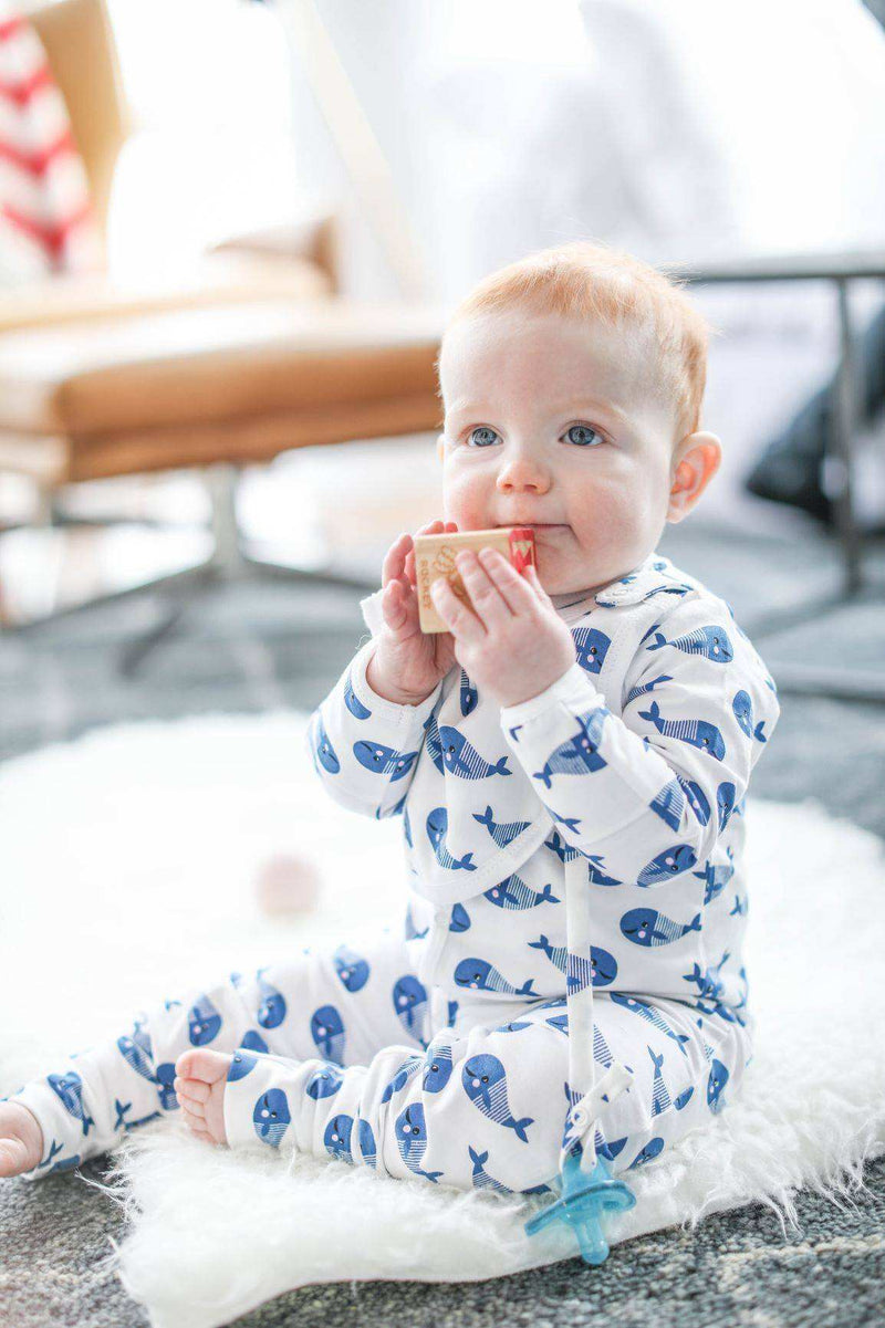 Footed one-piece with bib in blue whale print, made from organic cotton with convertible feet and hand covers.