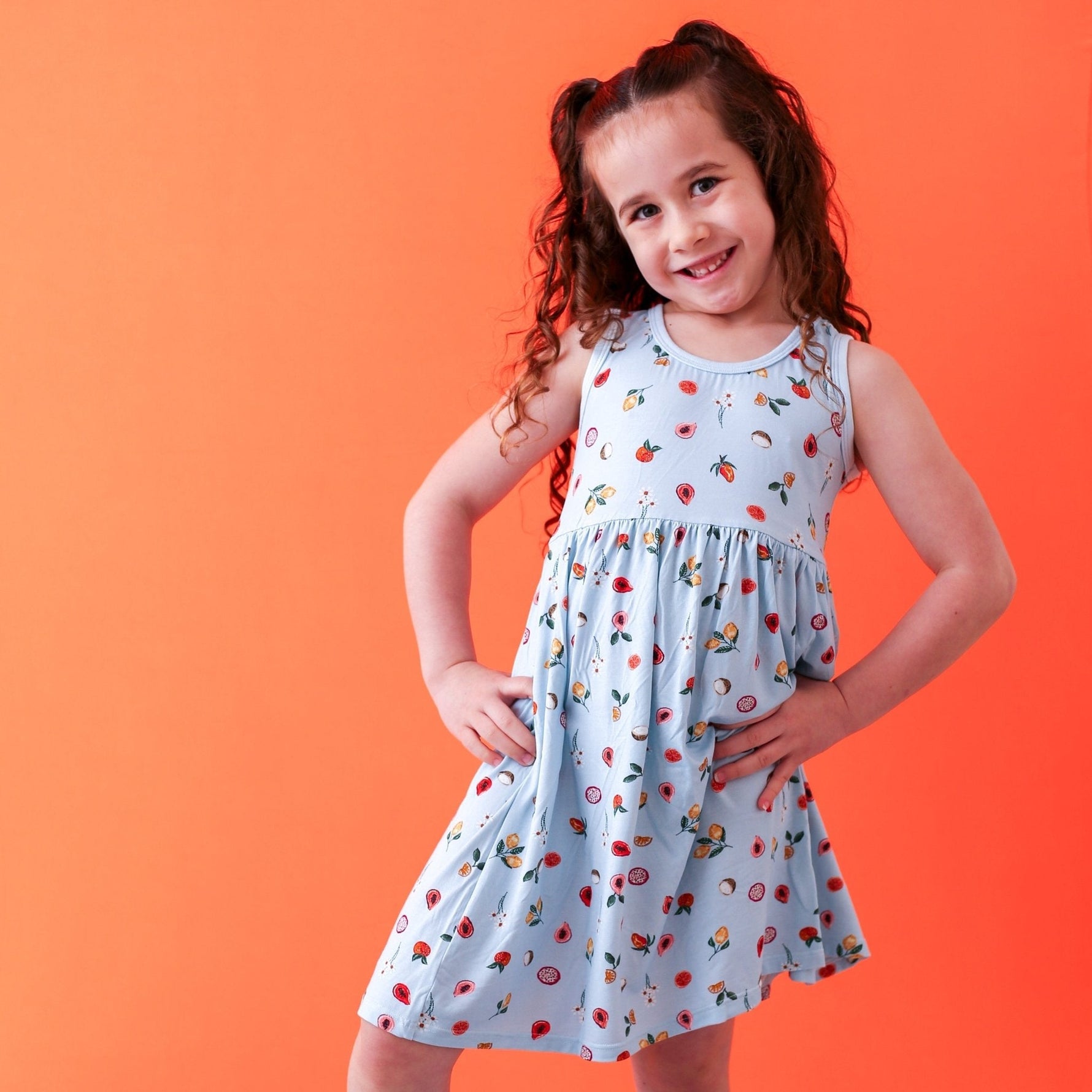 Toddler racer-back dress with long sleeves in a pink fruit print, worn by a young child