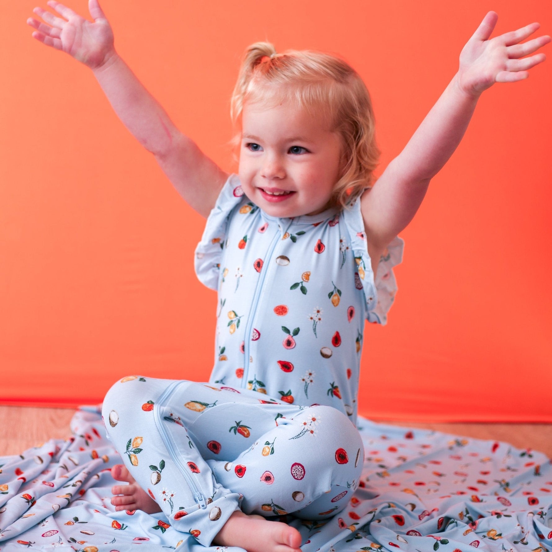Flutter sleeve baby romper in a pink fruit print with dual front zippers.