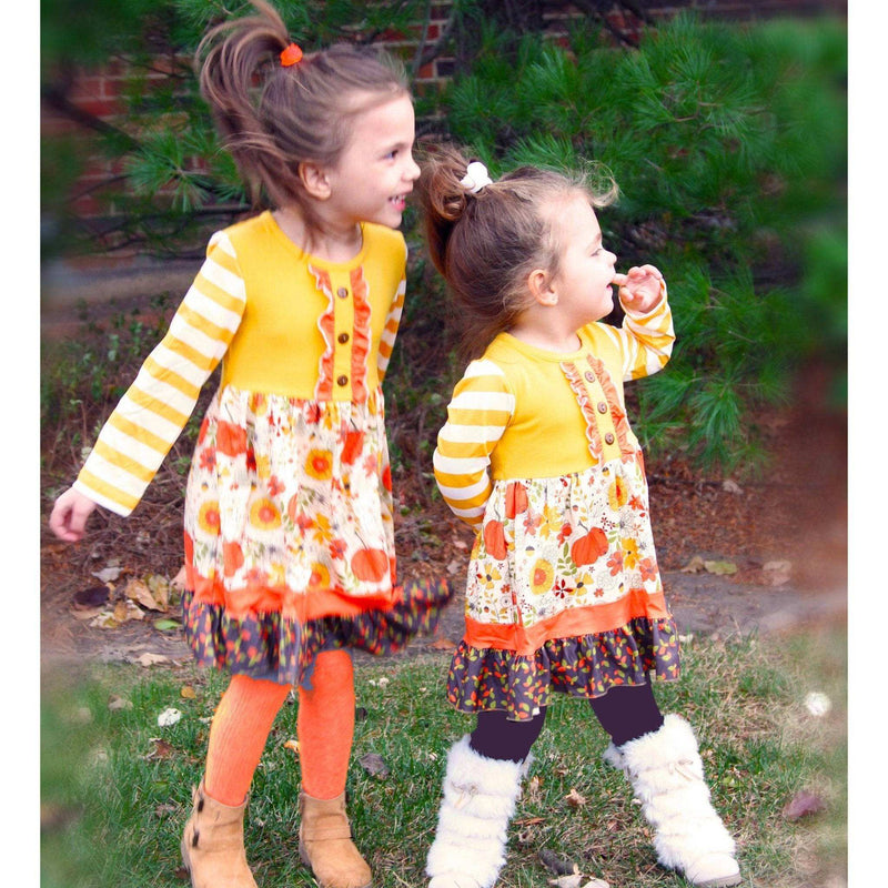 Girls wearing long sleeve fall pumpkin dresses with autumn floral prints and mustard yellow striped sleeves.