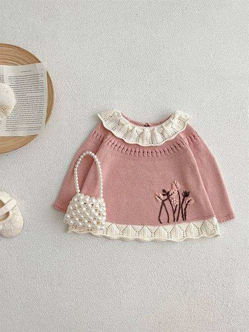 Girls' pink sweater with scalloped design and floral embroidery.