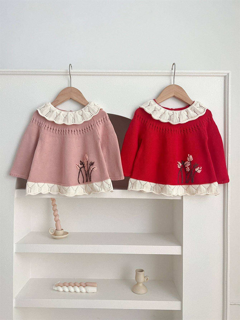 Pink and red girls' dresses with scalloped collar design hanging on a rack.