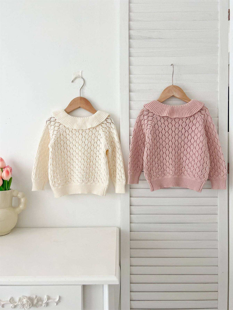  Girls Comfortable Sweater-out geometric sweaters in cream and pink hanging on a wall.