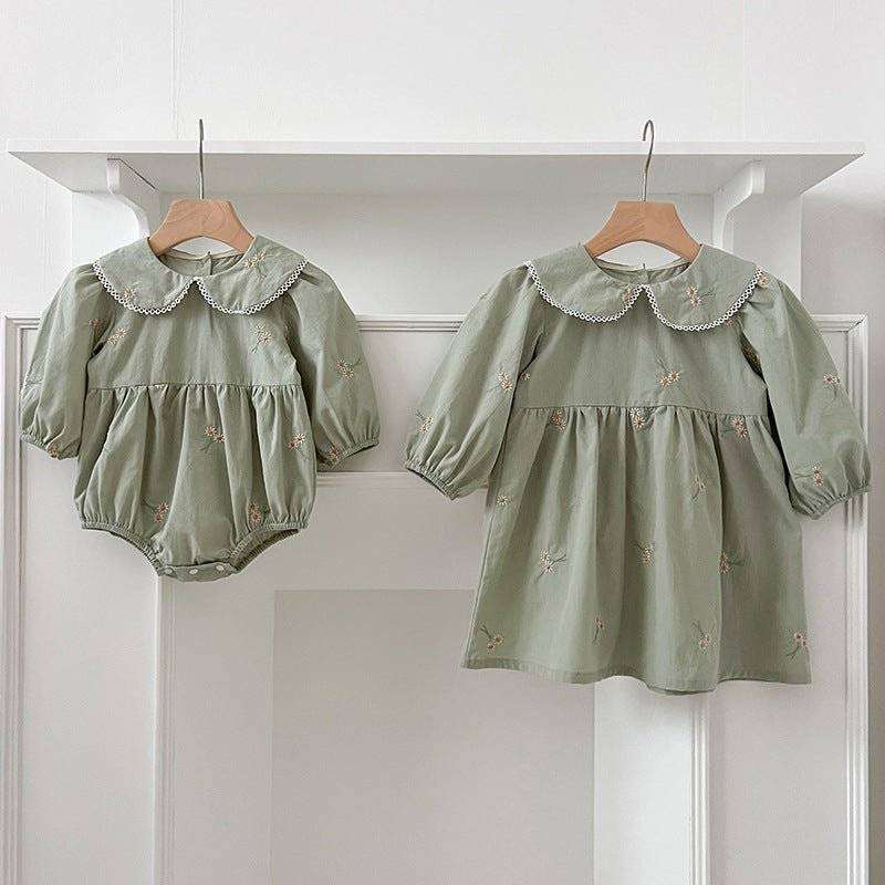 Girls long sleeves top with daisy floral embroidery hanging on hooks.