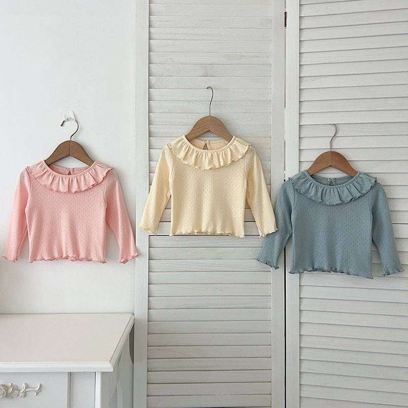 Girls soft comfortable long tops in pastel colors hanging on wooden hangers.