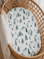 Soft organic bamboo changing pad cover in a green forest print, draped over a changing pad.