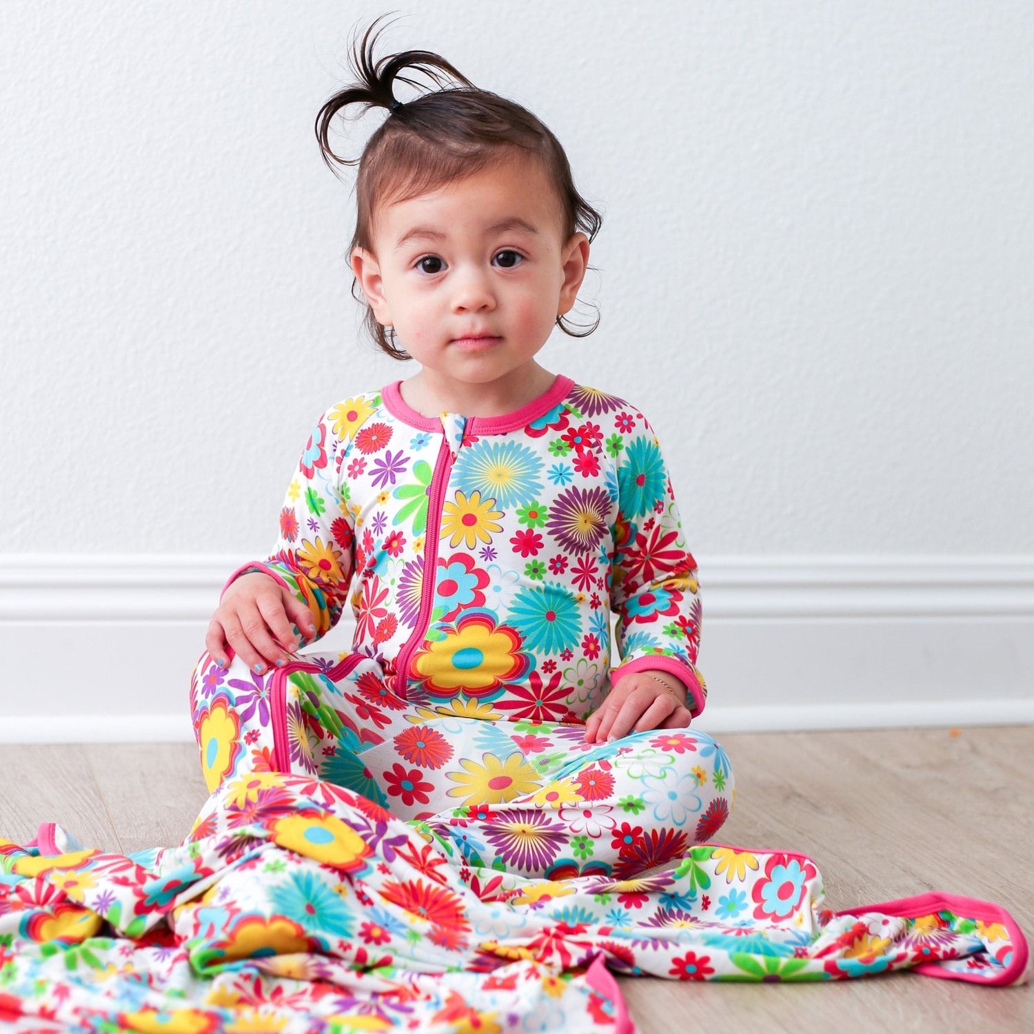 Baby footie pajamas in a retro 70s floral print with fold-over hand mittens and a front zipper.
