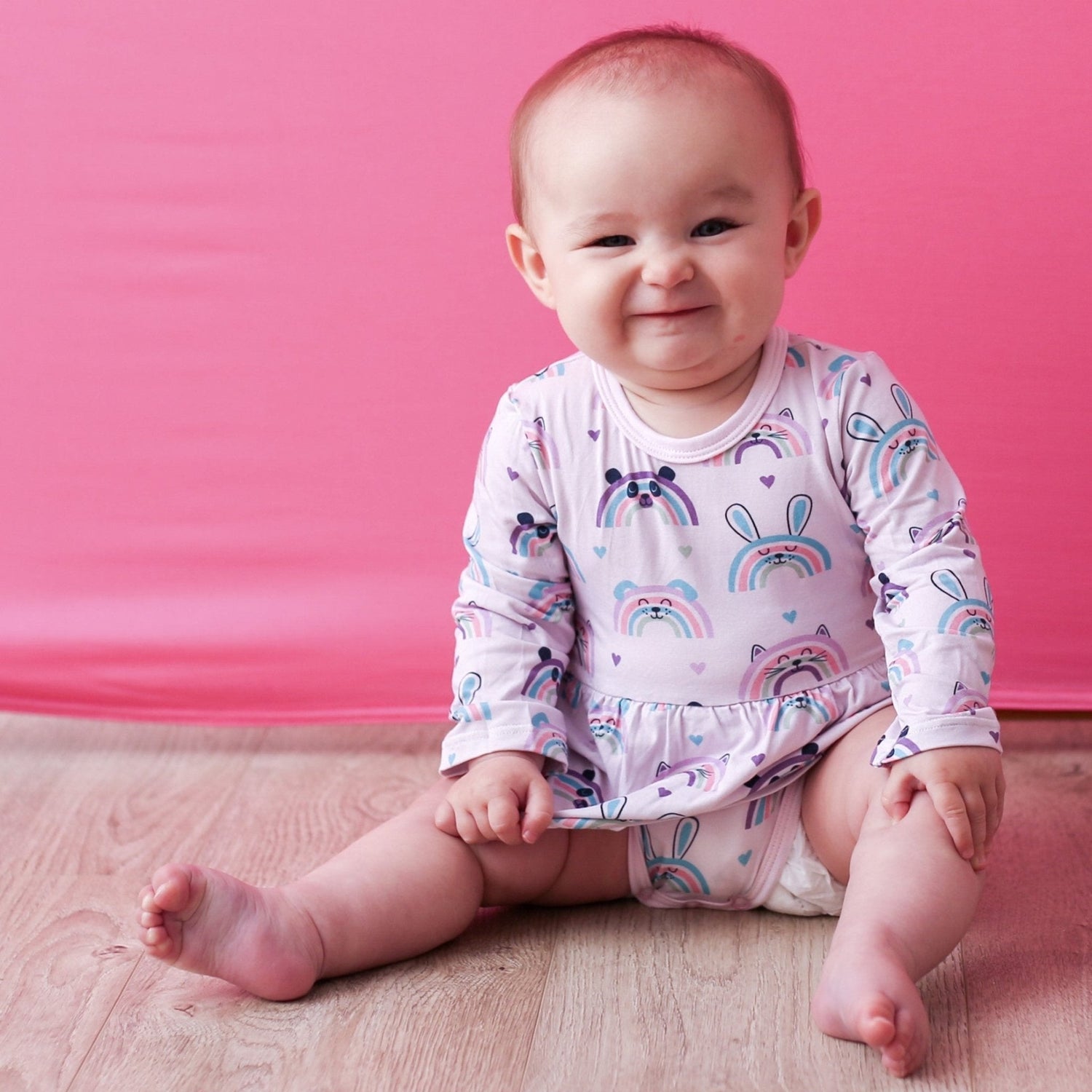 Bodysuit dress with a happy rainbow print, long sleeves, and snap closure at the inseam