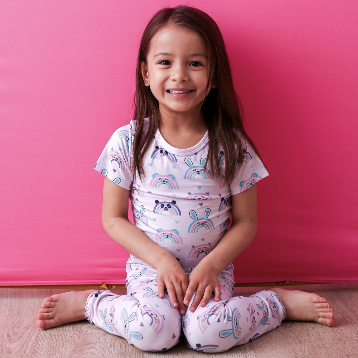 Short sleeve toddler pajama top and pants set with a pink rainbows and cute animals print.