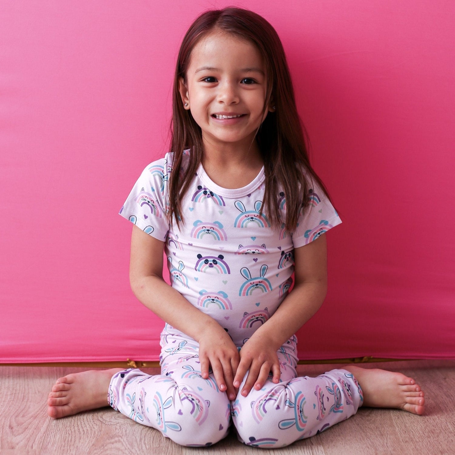 Short sleeve toddler pajama top and pants set with a pink rainbows and cute animals print.