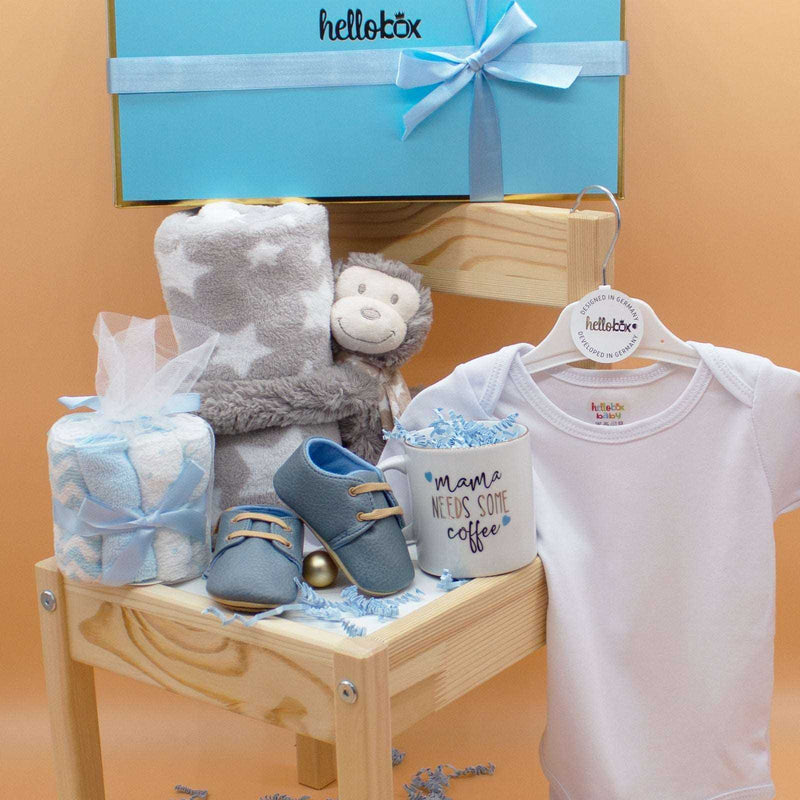 Baby Essential Set with blanket, plush toy, washcloths, onesie, moccasins, and mug in elegant box.