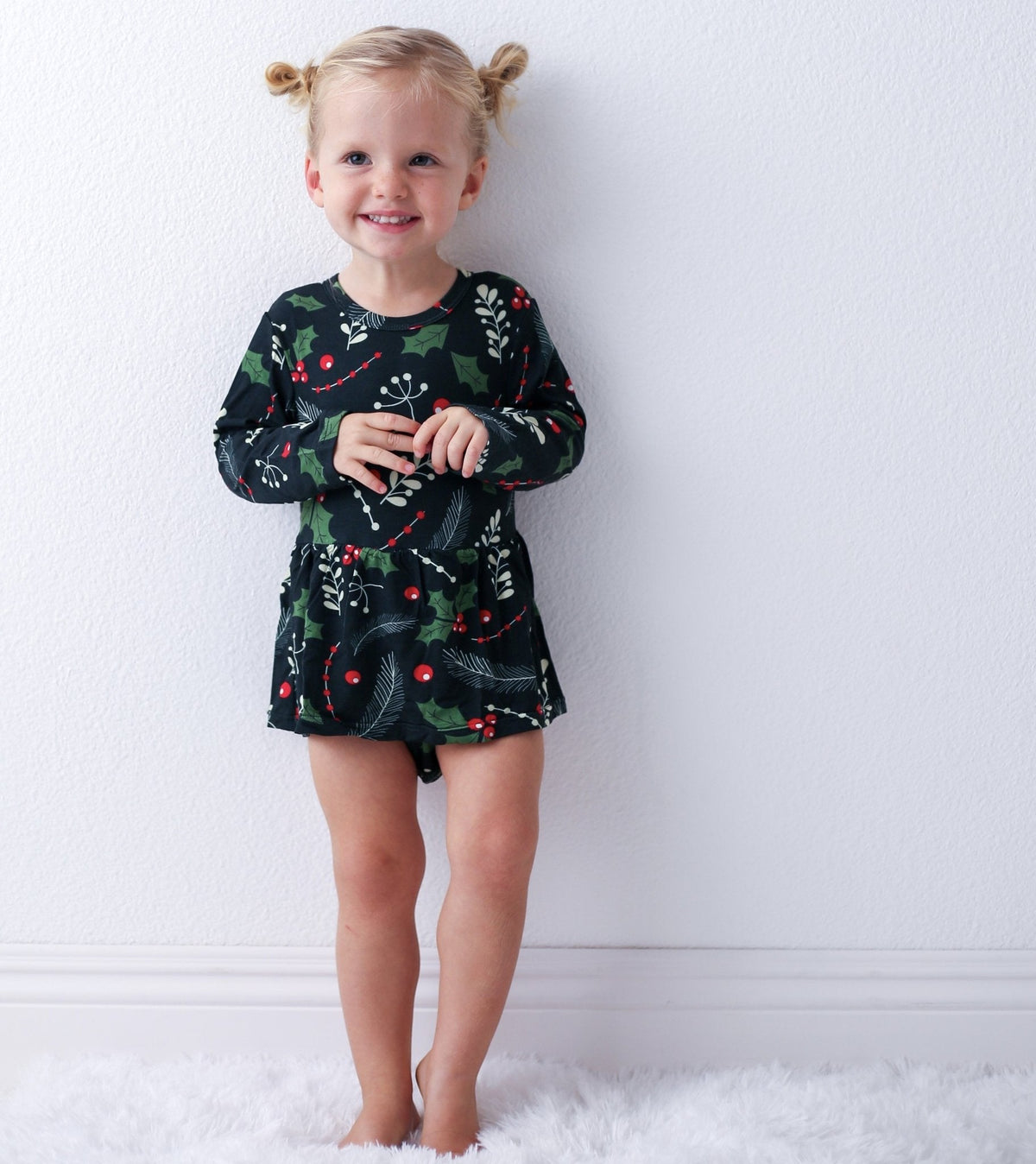 Holiday Nights bodysuit dress with long sleeves in a festive holiday print, worn by a smiling toddler
