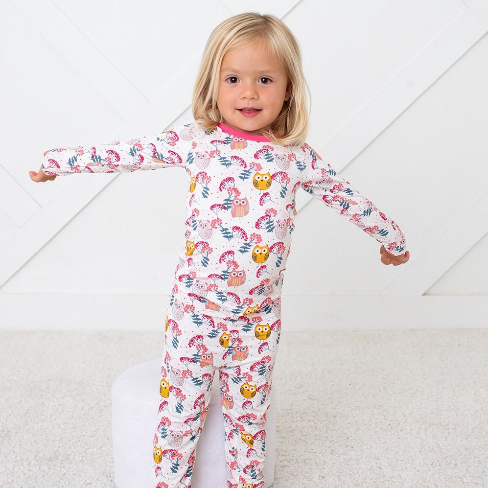 Long-sleeve pajama set with matching pants in a pink owl and floral print, worn by a smiling toddler.