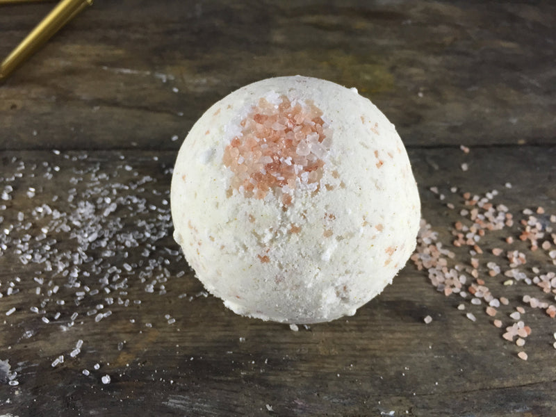 Large organic psoriasis/eczema bath bomb with pink sea salts on wooden surface.