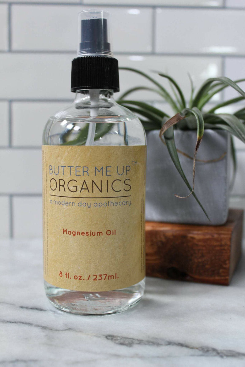 Magnesium Oil Spray in 8oz Glass Bottle by Butter Me Up Organics on Marble Counter with Plant