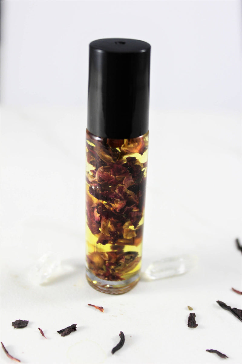 Organic perfume oil in a glass roll-on bottle with suspended rose petals, offering a natural, non-toxic fragrance.