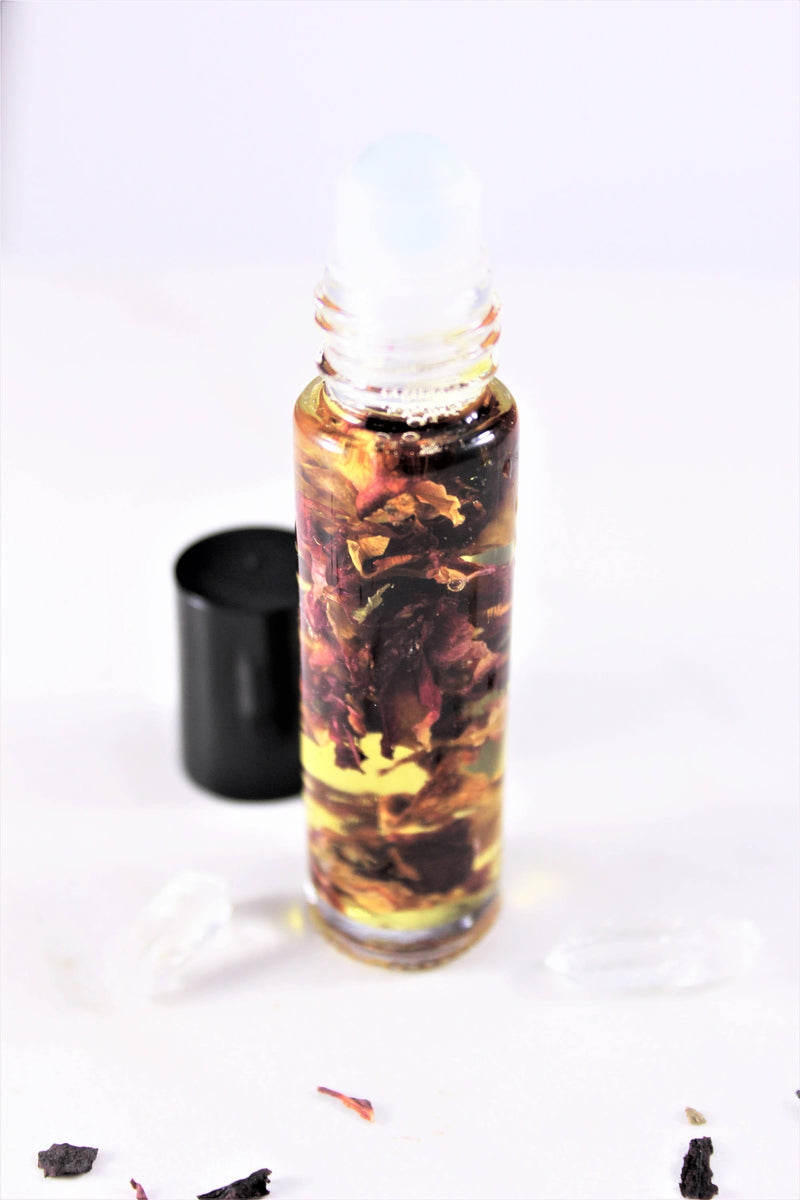 Organic perfume oil in a glass roll-on bottle with rose petals, eco-friendly and cruelty-free.