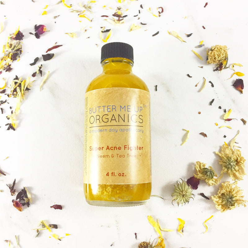 Organic Super Acne Fighter in glass bottle surrounded by dried flowers.