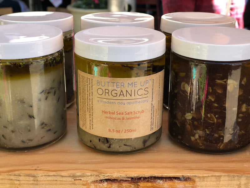 Organic sea salt herbal scrub jars on display, featuring natural exfoliating and nourishing ingredients in eco-friendly packaging.