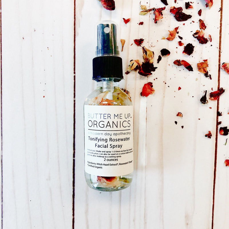Organic Rosewater Toner in glass bottle with scattered rose petals.