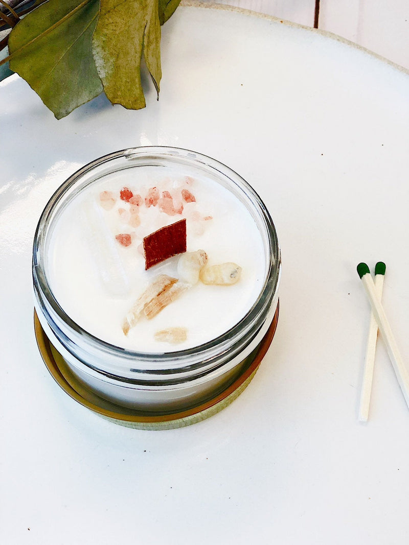 Organic soy space clearing candle with crystals, topped with palo santo and frankincense, for negative energy cleansing.