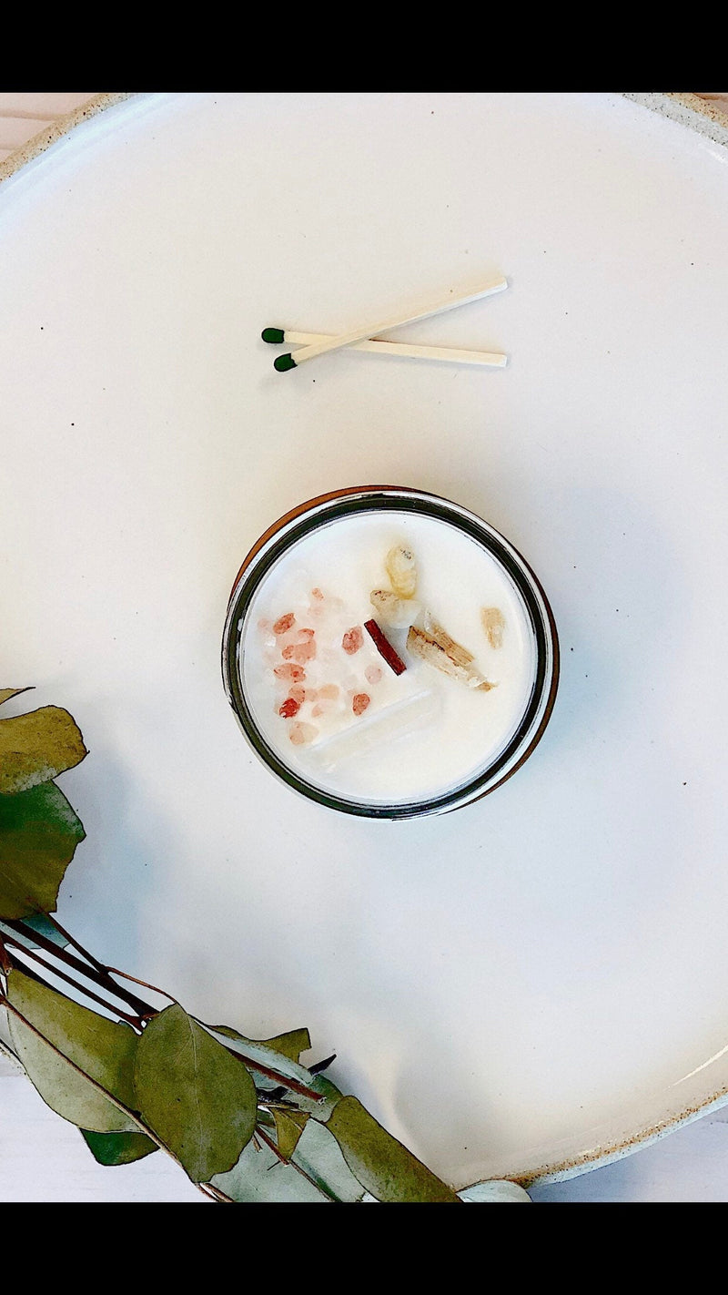 Organic soy space clearing candle topped with crystals and herbs, used for energy cleansing and intention setting.