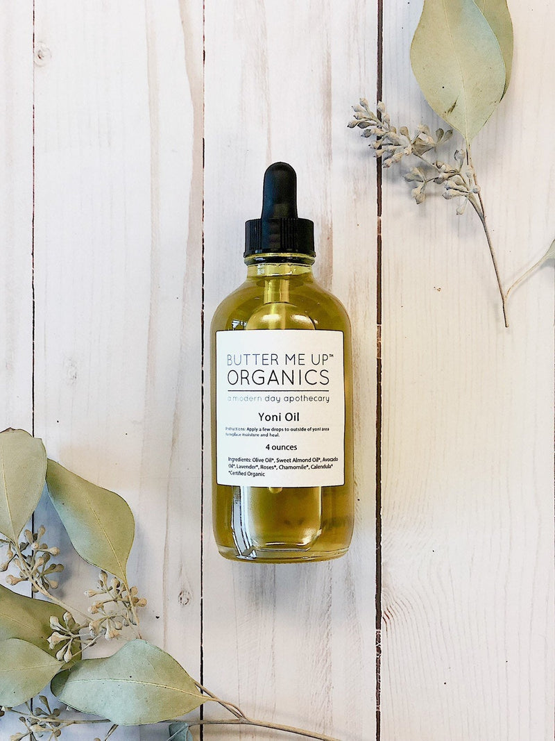 Organic Yoni Oil bottle with natural ingredients for feminine care on a wooden background.