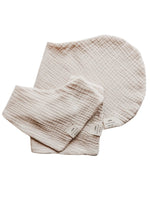 Close-up of an organic oat beige neutral baby bandana bib with a snap closure, folded neatly.