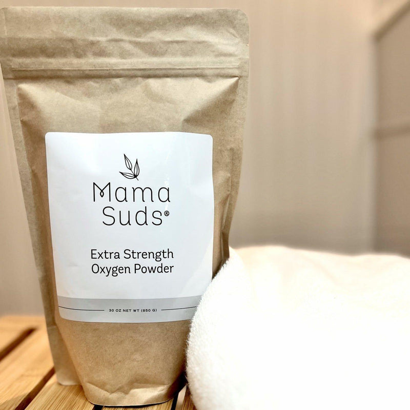MamaSuds Extra Strength Oxygen Powder package on wooden surface with white cloth, eco-friendly bleach alternative.